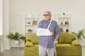 Senior man with a cast and on his broken arm and with a stick standing in the living room at home Royalty Free Stock Photo