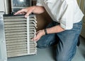 Senior man changing a dirty air filter in a HVAC Furnace