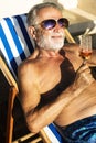 Senior man chilling and drinking wine on deck chair