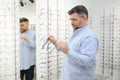 Senior man choosing glasses in optical store, try on eyeglass frames to decide on the perfect one Royalty Free Stock Photo