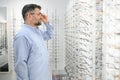Senior man choosing glasses in optical store, try on eyeglass frames to decide on the perfect one Royalty Free Stock Photo