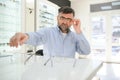 Senior man choosing glasses in optical store, try on eyeglass frames to decide on the perfect one Royalty Free Stock Photo