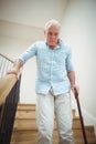 Senior man climbing downstairs with walking stick Royalty Free Stock Photo