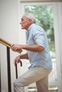 Senior man climbing upstairs with walking stick Royalty Free Stock Photo