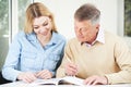 Senior Man Completing Crossword Puzzle With Teenage Granddaughter Daughter