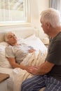 Senior man consoling of his sick wife in bed Royalty Free Stock Photo