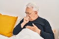 Senior man coughing sitting on bed at bedroom Royalty Free Stock Photo