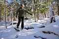 Senior Man Crossing a Fallen Log on snowshoes in forest