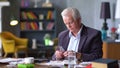 Senior man with cup of water and pill taking remedy in cozy room at home Royalty Free Stock Photo