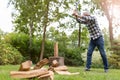 Senior man cutting logs with axe in yard focus on axe Royalty Free Stock Photo