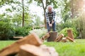 Senior man cutting logs with axe in yard focus on axe Royalty Free Stock Photo