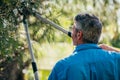 Senior man cutting trimming tree branches outside in the garden