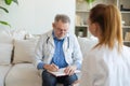 Senior man doctor examining yound woman in doctor office or at home. Girl patient and doctor have consultation in Royalty Free Stock Photo