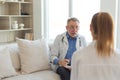 Senior man doctor examining yound woman in doctor office or at home. Girl patient and doctor have consultation in Royalty Free Stock Photo