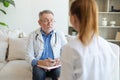 Senior man doctor examining yound woman in doctor office or at home. Girl patient and doctor have consultation in Royalty Free Stock Photo