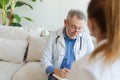 Senior man doctor examining yound woman in doctor office or at home. Girl patient and doctor have consultation in Royalty Free Stock Photo