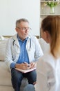 Senior man doctor examining yound woman in doctor office or at home. Girl patient and doctor have consultation in Royalty Free Stock Photo