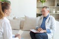 Senior man doctor examining yound woman in doctor office or at home. Girl patient and doctor have consultation in Royalty Free Stock Photo