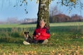 Senior man with dog sitting on grass leaning on tree