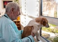 Senior man with dog sitting beside window