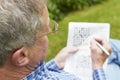 Senior Man Doing Crossword Puzzle In Garden Royalty Free Stock Photo
