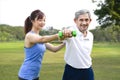 senior man doing exercise with daughter in the nature park,young asian woman train her father using dumbbell Royalty Free Stock Photo