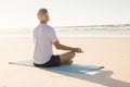 Senior man doing yoga at beach