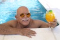 Senior man drinking cocktail in swimming pool Royalty Free Stock Photo