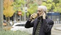 Senior man drinking coffee and talking on phone outdoors Royalty Free Stock Photo