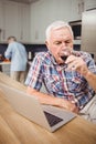 Senior man drinking red wine while using laptop Royalty Free Stock Photo