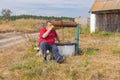 Senior man drinking water sitting on a bench near an old draw-well