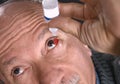 Senior man dripping a red bloodshot eye with eye drops Royalty Free Stock Photo