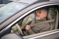 Senior man driving his modern car, going in reverse, watching ou Royalty Free Stock Photo