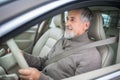 Senior man driving his modern car, going in reverse, watching out not to hit anything or anyone (color toned image; shallow DOF) Royalty Free Stock Photo