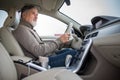 Senior man driving his modern car, going in reverse, watching out not to hit anything or anyone (color toned image; shallow DOF) Royalty Free Stock Photo