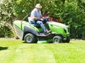 Senior man driving a tractor lawn mower in garden with flowers Royalty Free Stock Photo
