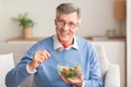 Senior Man Eating Vegetable Salad Sitting On Couch At Home Royalty Free Stock Photo
