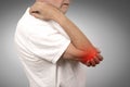 Senior man with elbow inflammation colored in red suffering from pain