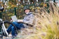 A senior man with electrobike sitting on a bench outdoors in town, using laptop. Royalty Free Stock Photo