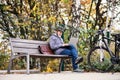 A senior man with electrobike sitting on a bench outdoors in town, using laptop. Royalty Free Stock Photo