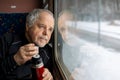 Senior man enjoying fresh tea during travel by train during winter time, traveling concept Royalty Free Stock Photo