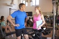 Senior Man Exercising On Cycling Machine Being Encouraged By Female Personal Trainer In Gym Royalty Free Stock Photo