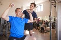 Senior Man Exercising With Weights Being Encouraged By Personal Trainer In Gym Royalty Free Stock Photo