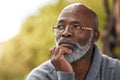 Senior man, face and thinking outdoor in nature to remember memory, idea or vision. Headshot of an elderly African male Royalty Free Stock Photo