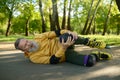 Senior man feeling pain in knee falling down while roller skating in park Royalty Free Stock Photo