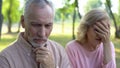 Senior man feeling sad and guilty, wife crying sitting apart, couple divorce