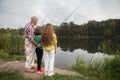 Senior man fishing on lake with his grandchildren Royalty Free Stock Photo