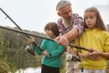 Senior man fishing on lake with his grandchildren Royalty Free Stock Photo