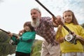 Senior man fishing on lake with his grandchildren Royalty Free Stock Photo
