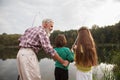 Senior man fishing on lake with his grandchildren Royalty Free Stock Photo